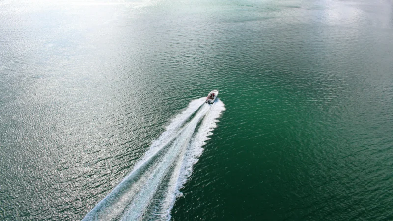 Bateau à moteur laissant un sillage sur une mer calme, vu du ciel