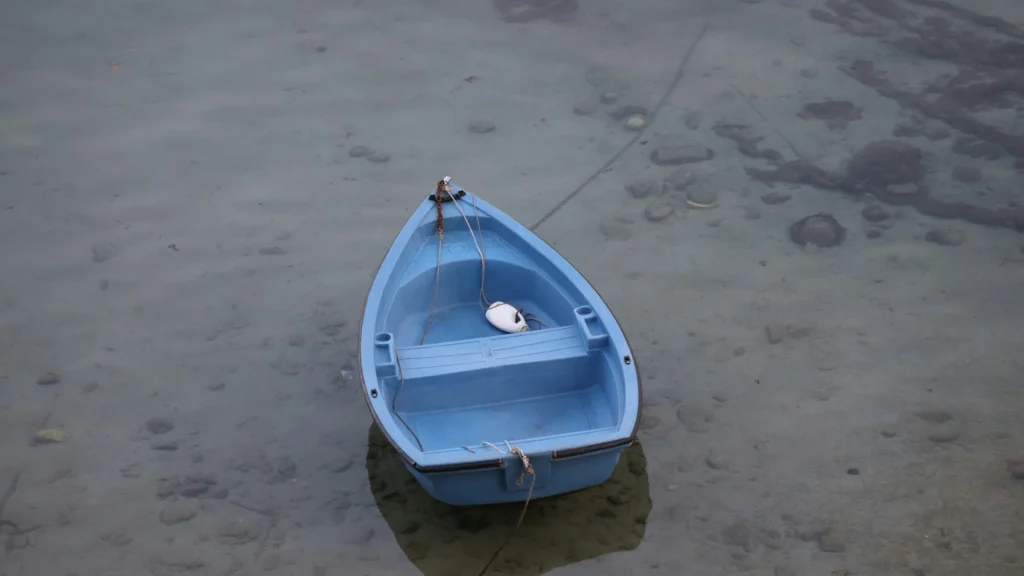 Petit bateau bleu sur une eau claire et peu profonde