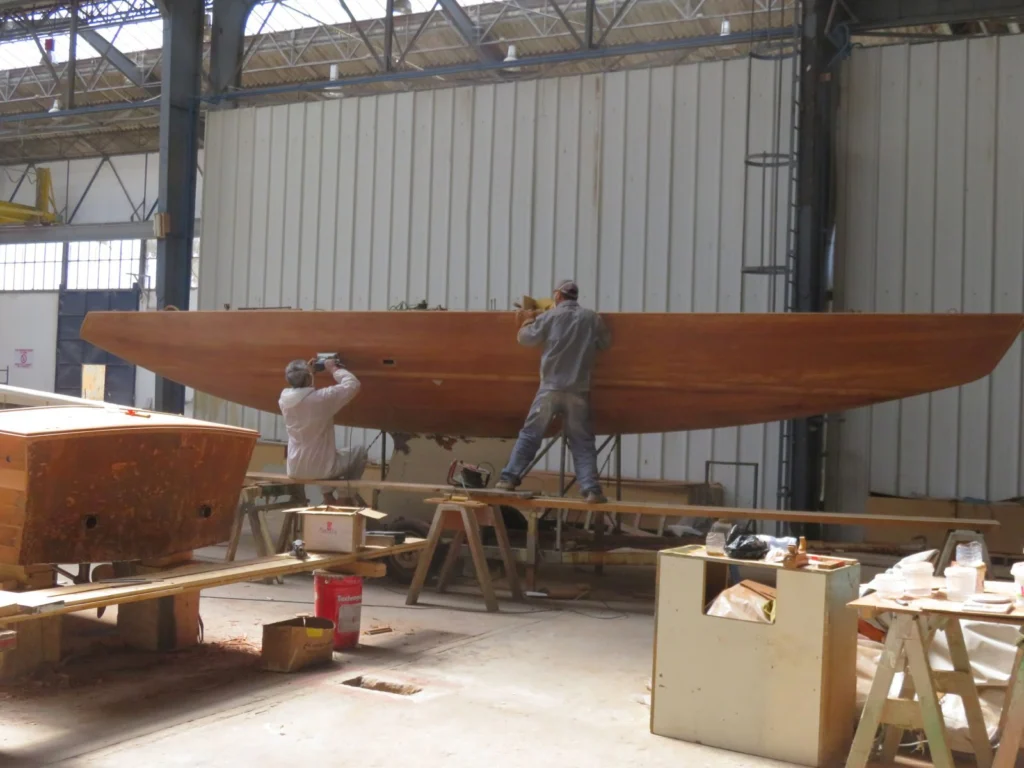 Menuiserie navale sur la coque en bois d'un voilier 5.5 au Chantier Naval de la Méditerranée