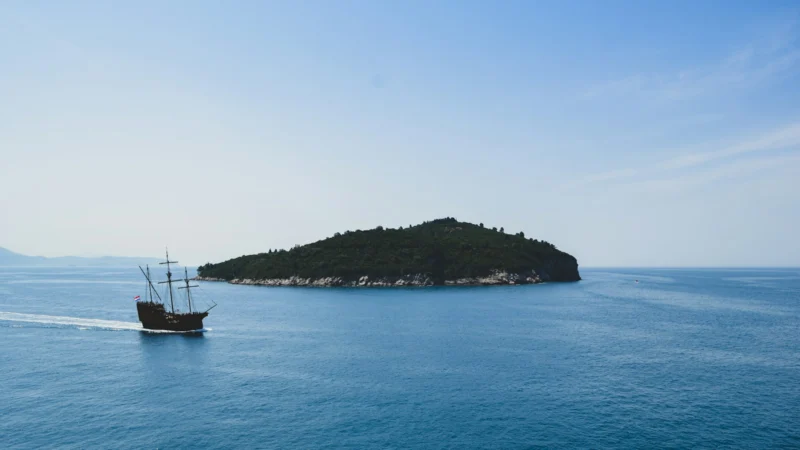 Bateau naviguant près d'une île méditerranéenne par beau temps