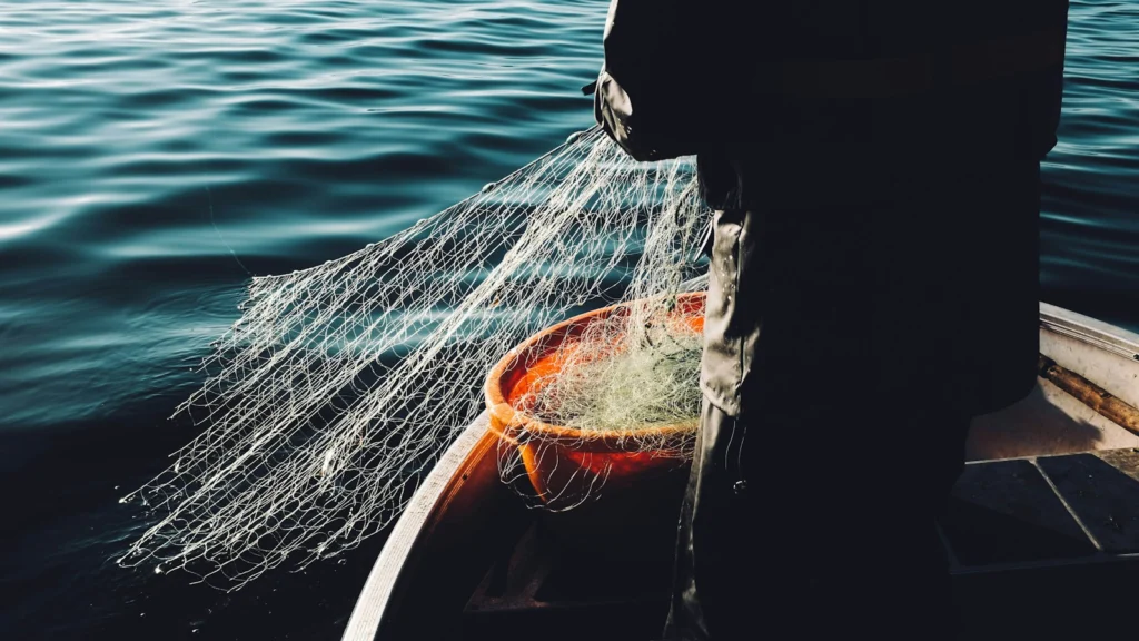 Pêcheur lançant un filet depuis un bateau en mer